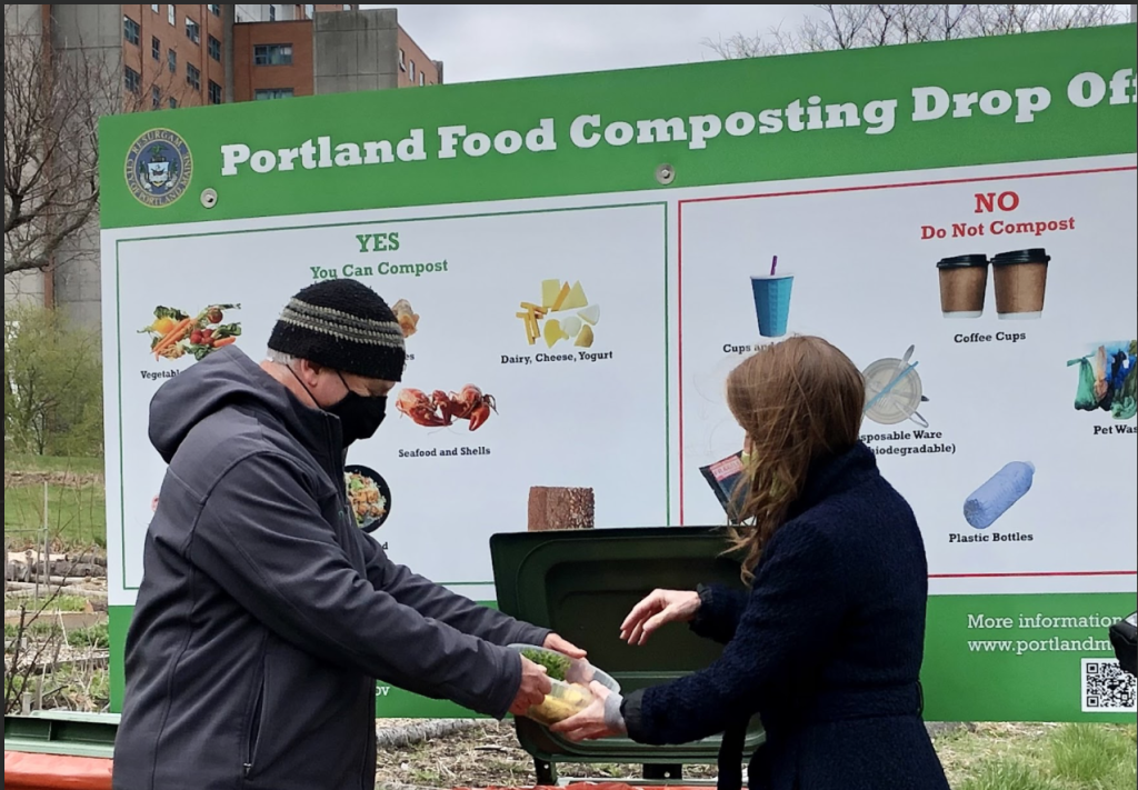 Two people putting compost into a compost bin